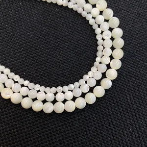 Macro shot of white shell round beads with pearlescent luster on black textured fabric