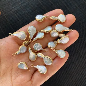 Detailed view of natural baroque pearls with gold edges held in hand for scale