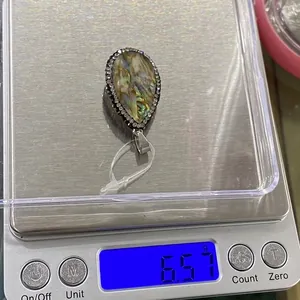 Vue détaillée d'un pendentif goutte en nacre d'abalone avec strass blancs sur une balance