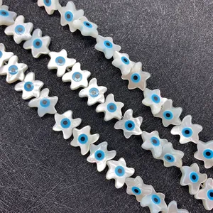 Macro shot of white star-shaped mother of pearl beads with blue evil eye pattern