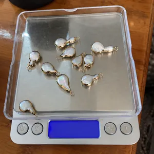 Detailed close-up of nine irregular freshwater pearl gourd pendants on a digital scale