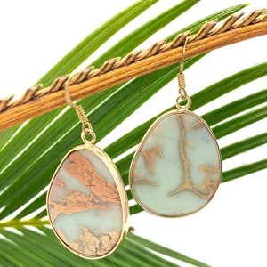 Waterdrop-shaped natural stone earrings in gold frame hanging on a natural branch