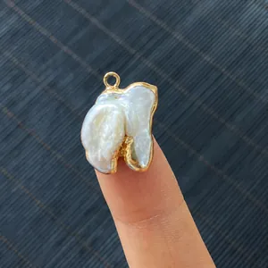 Detalle de colgante de perla barroca con borde dorado mostrado sobre la mano