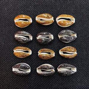 Detailed macro view of gold and black glitter coated natural cowrie shell beads for DIY jewelry