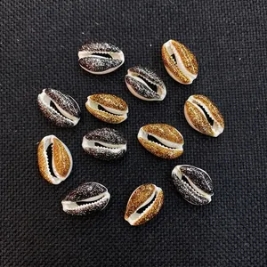 Macro detail of natural cowrie shells with gold and black glitter for DIY jewelry making