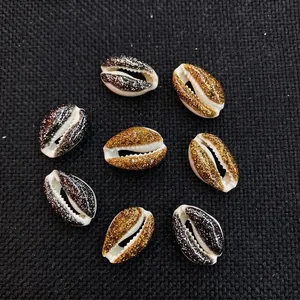 Macro shot of gold and black glitter coated natural cowrie shell beads for DIY jewelry