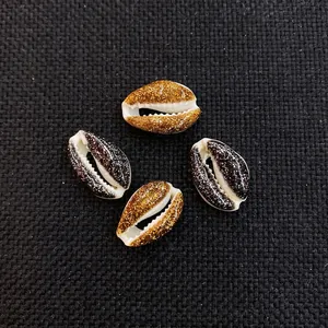 Macro view of natural cowrie shells with gold and black glitter coating for DIY jewelry
