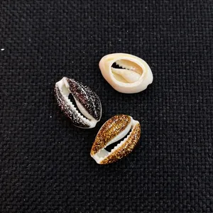 Macro shot of natural cowrie shells in white, gold, and black glitter for DIY jewelry