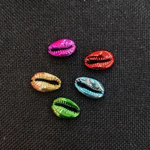 Dettaglio di conchiglie colorate placcate in metallo per gioielli DIY su tessuto nero