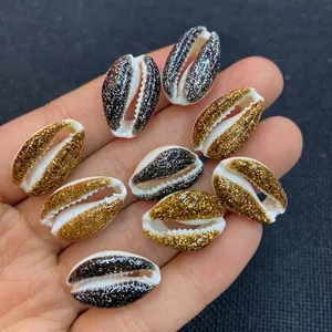 Macro detail of glittered natural cowrie shells in gold and black for DIY jewelry crafts
