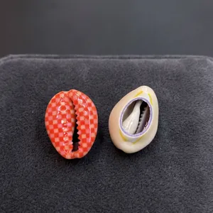 Nahaufnahme von Bastelmuscheln mit orangefarbenem Karomuster und lila Naturkanten-Details