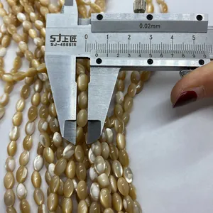 Makroansicht der Messung goldener Muschelperlen mit einem Messschieber für DIY-Schmuck