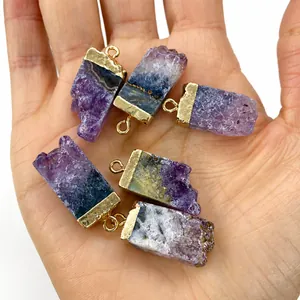 Nahaufnahme unregelmäßiger Amethyst-Anhänger mit Goldkappen in der Hand gehalten