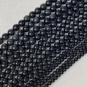 Polished black gemstone beads in various sizes for DIY jewelry making on grey fabric