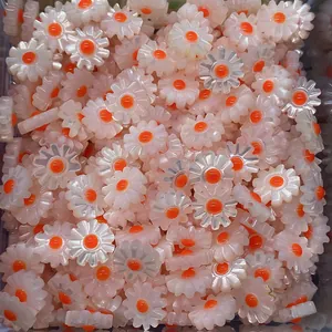 Macro view of white daisy beads with orange centers for DIY jewelry crafting