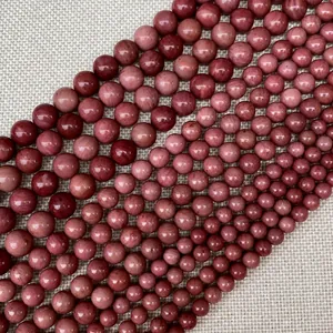 Vue détaillée des perles rondes en pierre de rhodonite aux tons roses et marbrés
