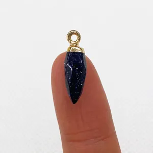 Blue goldstone bullet pendant held on fingertip showing small 6x20mm scale for jewelry making