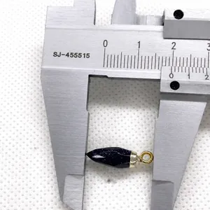 Macro view of blue sandstone bullet pendant with gold ring measured by caliper