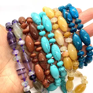 Colorful natural stone tube beads and flat spacers shown in a hand-held closeup view