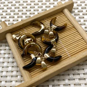 Détail de pendentifs œil de tigre en demi-lune avec attaches dorées sur plateau
