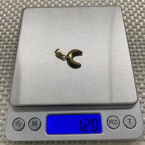 Détail macro du pendentif œil de tigre en forme de lune pesant 1,20 g sur une balance