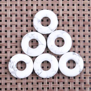 Sechs weiße Türkis-Donut-Anhänger mit grauer Maserung auf gewebtem Hintergrund