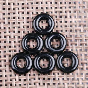 Detailansicht von sechs schwarzen Obsidian-Donut-Anhängern auf gewebtem Grund