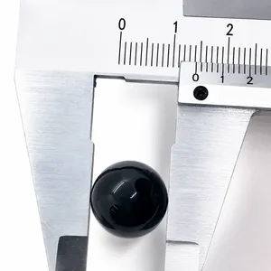 Gros plan d'une perle en pierre noire polie de 16mm mesurée avec un pied à coulisse