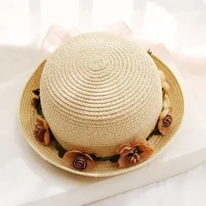 Detailed view of beige straw hat with silk flowers and elegant pink ribbon bow
