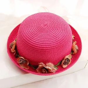 Detailed close-up of pink straw sun hat with delicate silk flower decorations