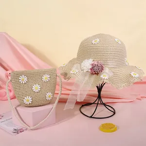 Dettaglio del set cappello di paglia beige e borsa con margherite bianche e nastro floreale