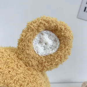 Détail de la texture douce en polaire jaune sur le cache-oreille du bonnet bébé