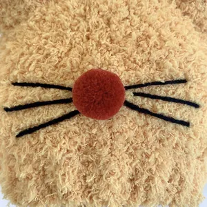 Gros plan sur un bonnet en peluche gingembre avec texture laine d'agneau et nez pompon rouge