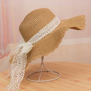 Women's French straw sun hat with wavy brim and white lace bow for beach vacation