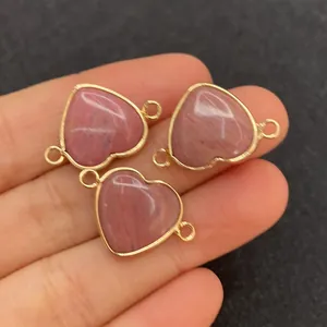 Detalle de conectores de piedra rosa en forma de corazón con borde dorado para joyería