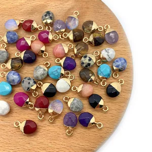 Kleurrijke ovale edelsteen hangers met vergulde ringen op een ronde houten tray