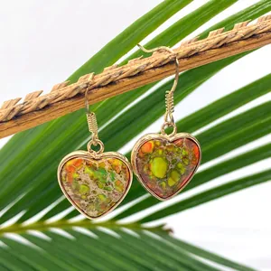 Macro shot of heart-shaped natural stone earrings hanging on a rustic wood branch