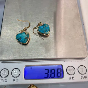 Detailed view of bohemian heart-shaped turquoise earrings on a scale weighing 3.88g