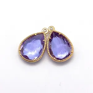 Detailed view of faceted purple crystal teardrop charms with gold beaded metal edges