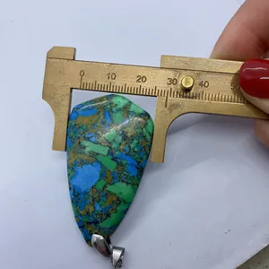 Vue macro d'un pendentif turquoise mesuré au pied à coulisse indiquant 32 mm de large