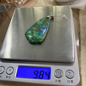 Pendentif goutte en turquoise sur une balance électronique affichant un poids de 9,84g