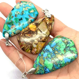 Trois pendentifs gouttes en turquoise naturelle avec fermoirs argentés dans une main