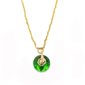 Detailed view of a faceted green crystal pendant with golden rose accent on a gold chain