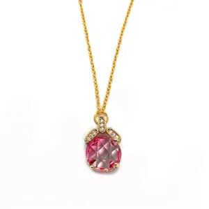 Macro shot of faceted pink crystal pineapple pendant with a gold chain and zircon inlay