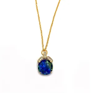 Macro shot of faceted blue-green crystal pendant with gold setting and small zircons