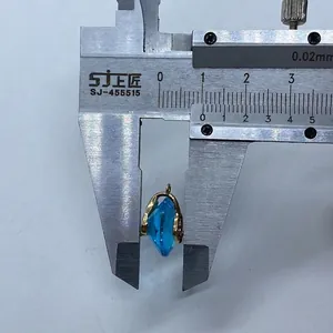 Blue marquise-cut stone pendant with gold edge measured by caliper for size scale