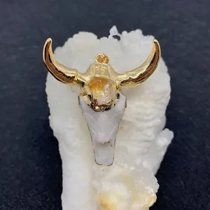 Dettaglio macro del ciondolo a teschio di toro dorato con resina bianca e ambra
