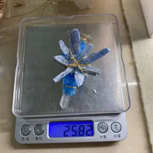 Close-up of a raw blue kyanite and crystal pendant being weighed on a digital scale