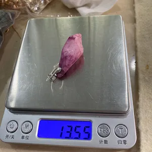 Dettaglio di un ciondolo in cristallo rosa pesato a 13,55 grammi su una bilancia digitale