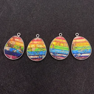 Detailopname van vier regenboogkleurige druppelhangers met zilveren randen op zwarte basis